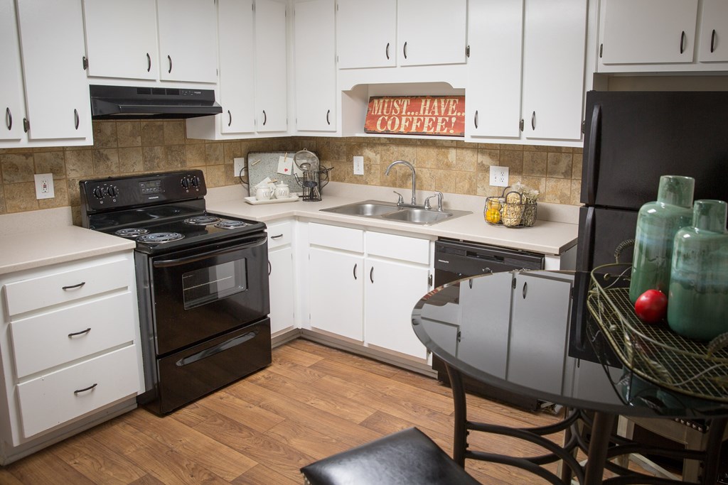 a kitchen with white cabinets and black appliances and a table