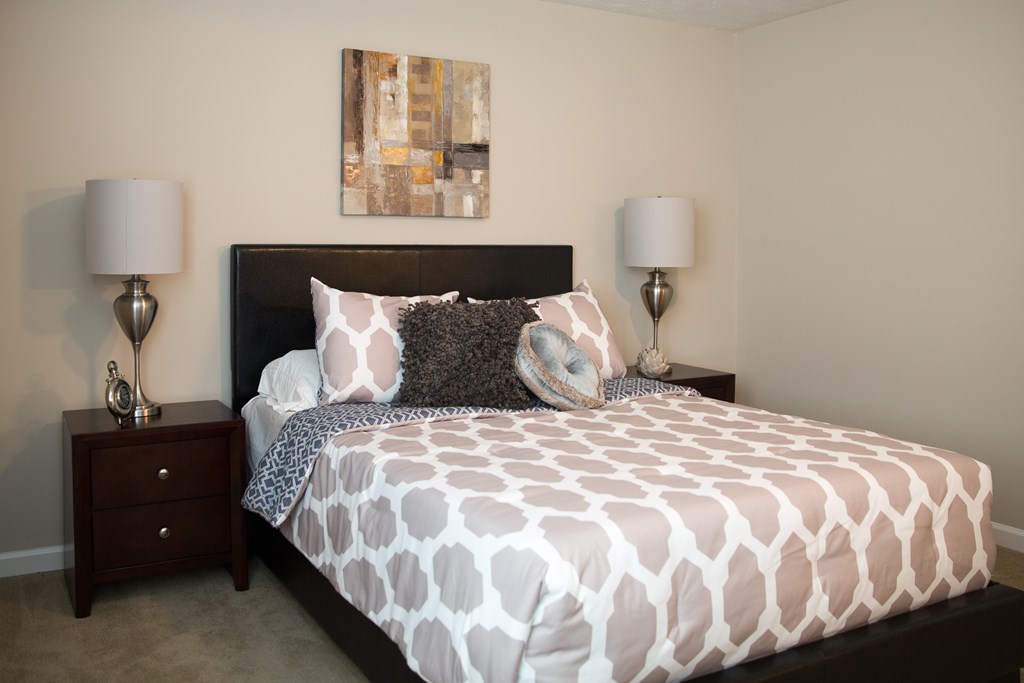 a bedroom with a bed and two nightstands and a painting on the wall