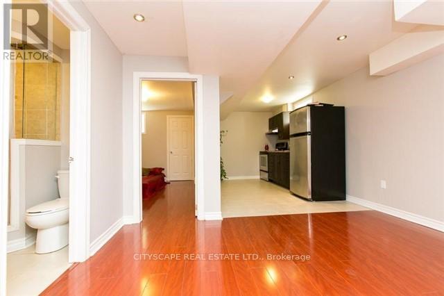 A spacious room with a wooden floor and a black refrigerator.