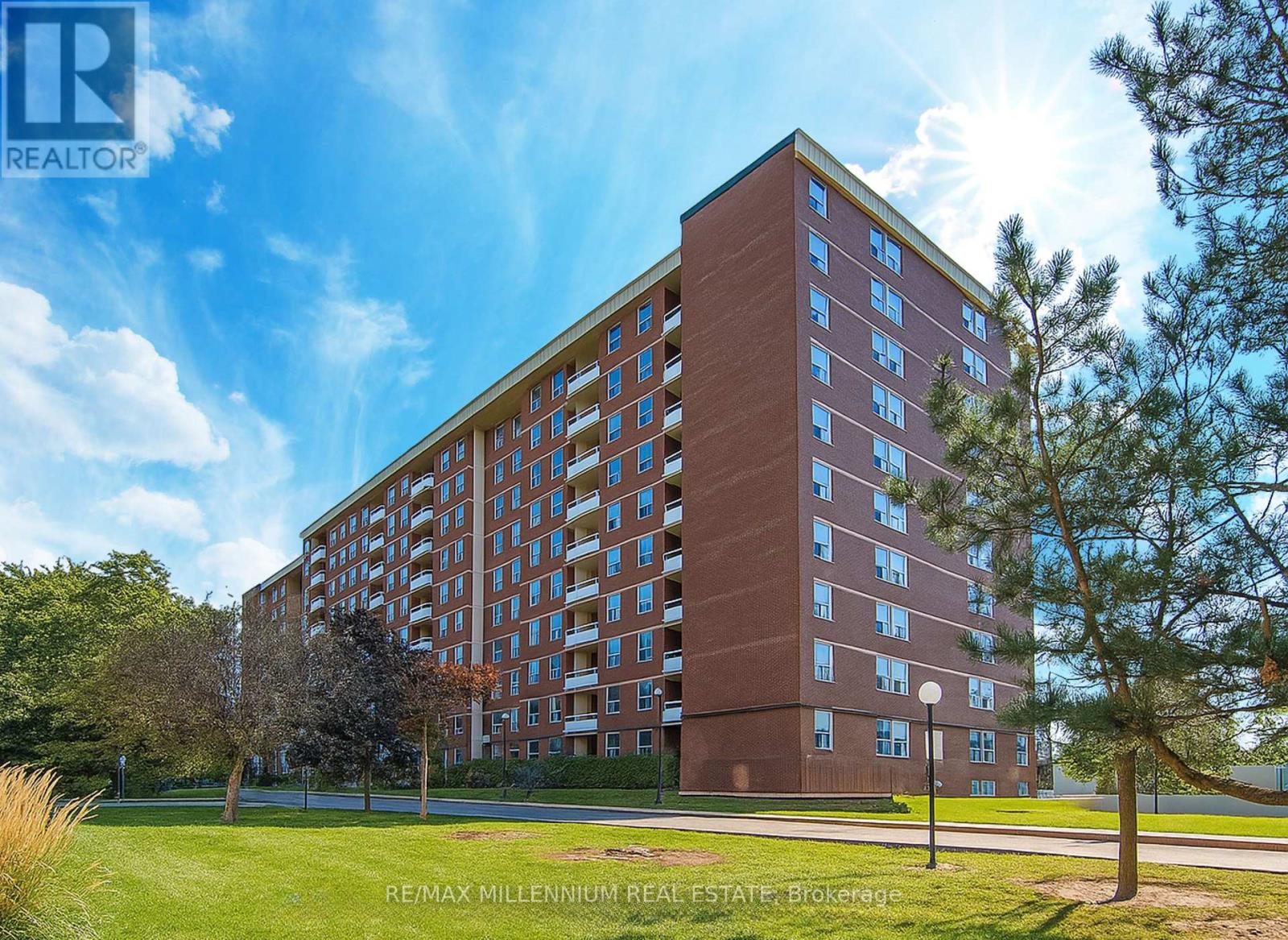 A tall red brick building with a blue sky and clouds in the background.
