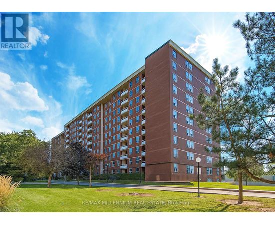 A tall red brick building with a blue sky and clouds in the background.