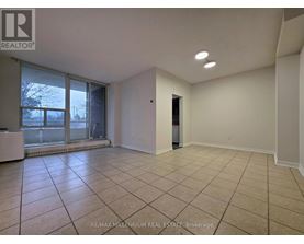 A spacious room with tiled flooring and a sliding glass door leading to a balcony.