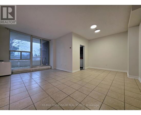 A spacious room with tiled flooring and a sliding glass door leading to a balcony.
