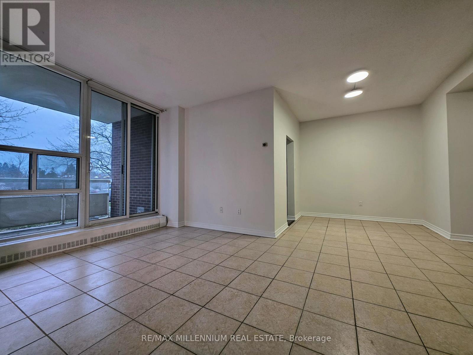 A spacious room with tiled flooring and white walls.