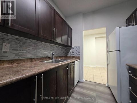 A kitchen with brown cabinets and a stone backsplash.