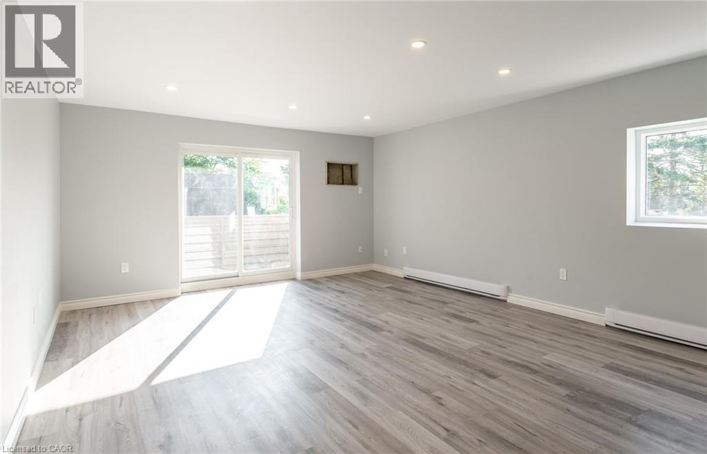 A spacious room with wooden flooring and a large window.