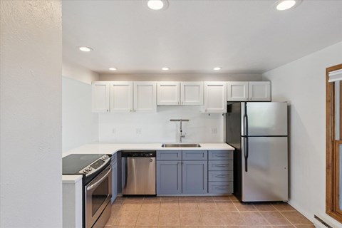 A kitchen with white cabinets and a stainless steel refrigerator.