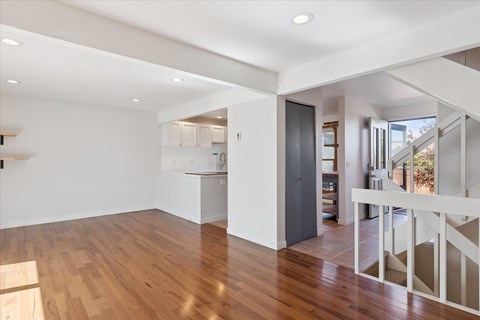 A spacious room with wooden floors and white walls.