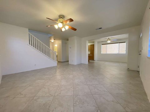 A spacious room with a ceiling fan and tiled flooring.