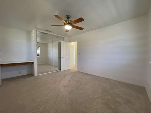 A room with a ceiling fan and carpeted floor.