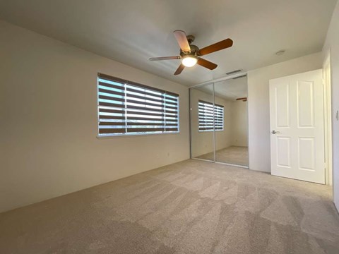 A room with a ceiling fan and a window with blinds.