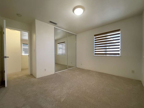 A room with a carpeted floor, a window with blinds, and a sliding glass door.