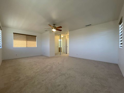A room with a ceiling fan and carpeted floor.