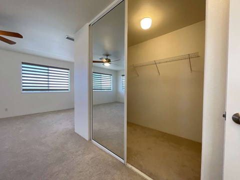 A room with a mirrored closet door and a ceiling fan.