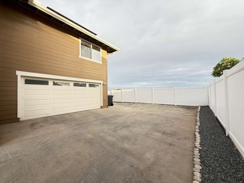 A brown house with a white garage door and a white fence.