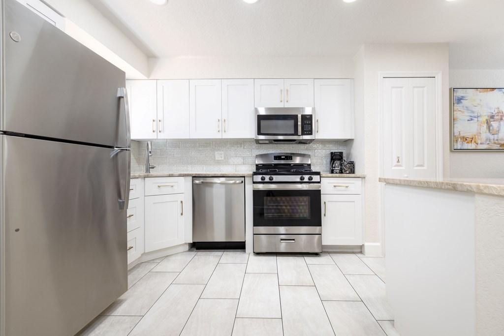 A modern kitchen with stainless steel appliances and white cabinets.