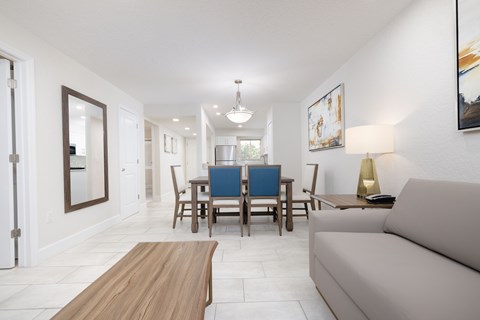 A living room with a couch, coffee table, and dining table.