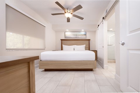 A bedroom with a bed, dresser, and ceiling fan.