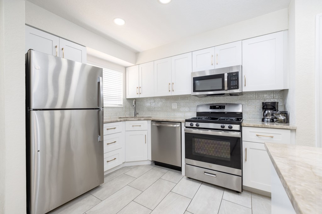 A modern kitchen with a stainless steel refrigerator, microwave, oven, and cabinets.