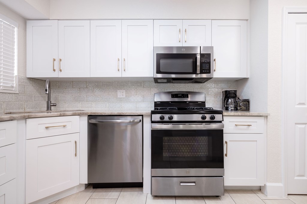 A kitchen with white cabinets and a black stove top oven.