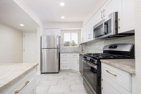 A kitchen with white cabinets and black appliances.