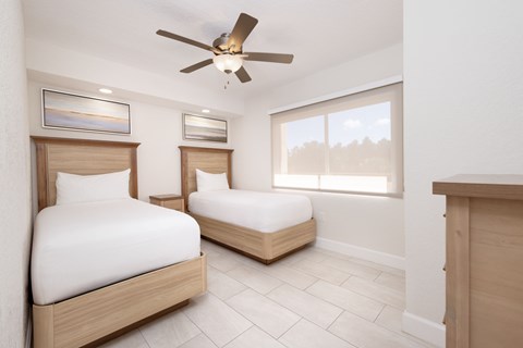 A bedroom with two beds and a ceiling fan.
