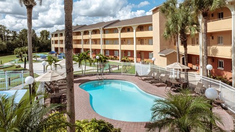 A large swimming pool surrounded by palm trees and lounge chairs.