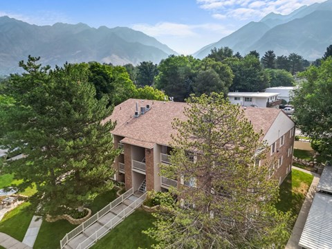 A building with a red roof is surrounded by trees and mountains.
