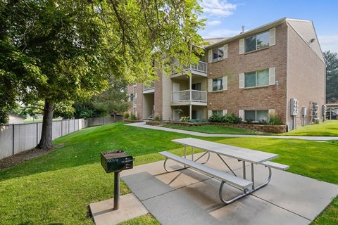 A concrete picnic table is in front of a brick building.