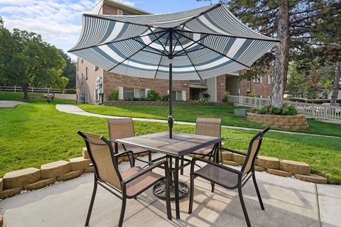 A patio with a table and chairs under a striped umbrella.