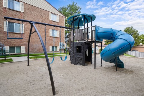 A playground with a blue slide and a sandbox.