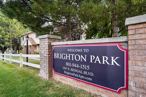 A sign welcoming people to Brighton Park with a phone number and address.