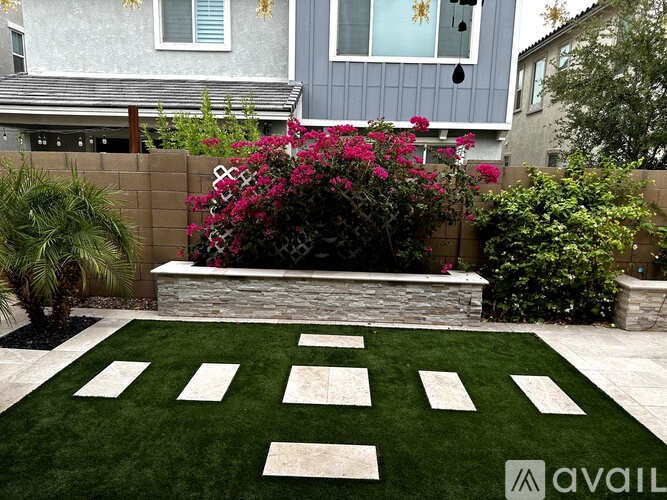 A garden with a white stone pathway and a grey house in the background.