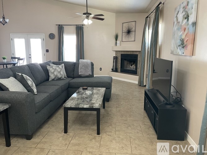 A living room with a grey couch, a coffee table, a fireplace, and a television.