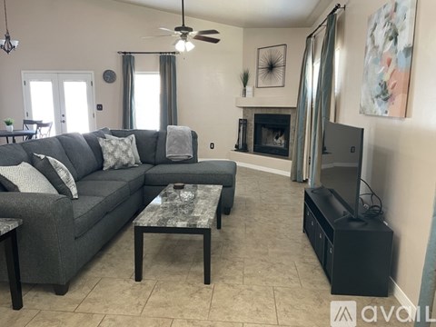 A living room with a grey couch, a coffee table, a fireplace, and a television.