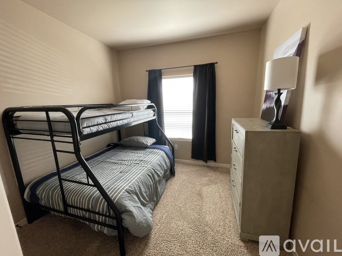 A bedroom with a bunk bed and a dresser with a lamp on top.