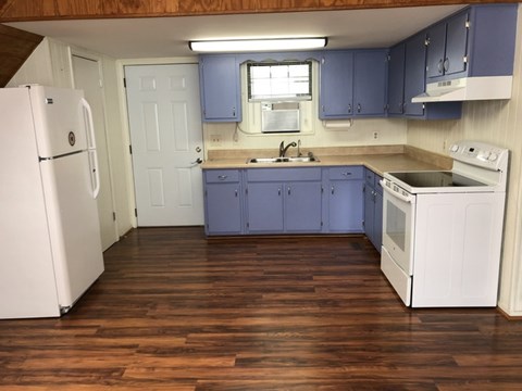 A kitchen with white appliances and wooden floors.