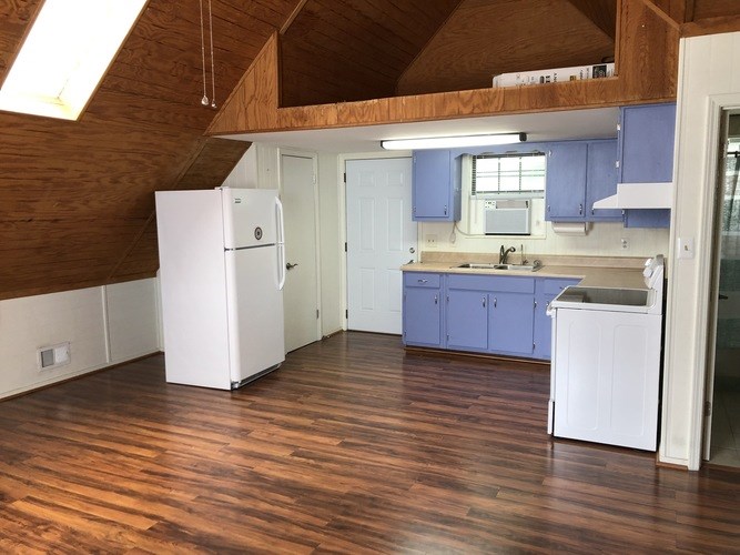 A kitchen with wooden floors and white appliances.