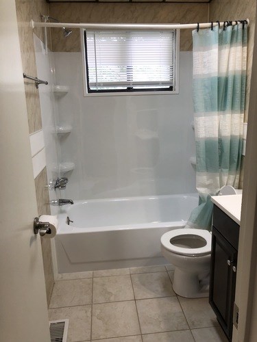 A bathroom with a toilet, a bathtub, and a shower curtain.