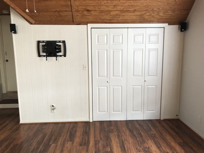A room with a white door and a black object on the wall.