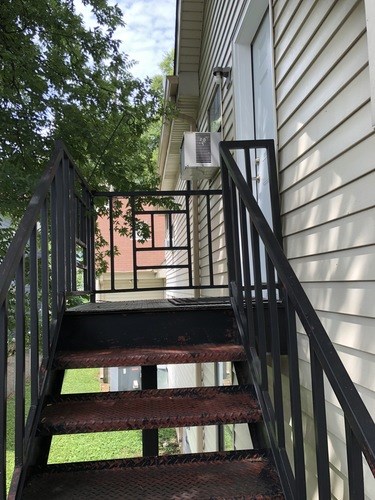 A staircase with a metal railing and steps leading up to a door.