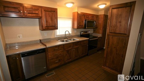 A kitchen with wooden cabinets and a stainless steel dishwasher.
