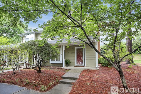 A house with a front yard and a tree in front of it.