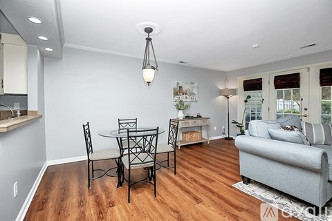 A dining table with four chairs is in the middle of a living room.