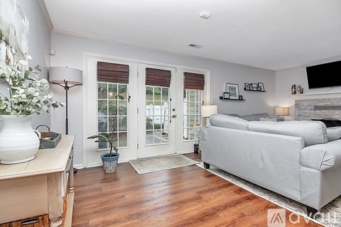A living room with a grey couch and a wooden floor.