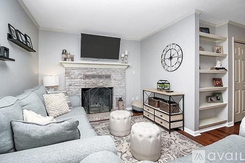 A living room with a grey couch, a fireplace, and a TV mounted above it.