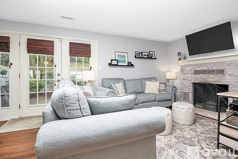 A living room with a grey couch and a fireplace.