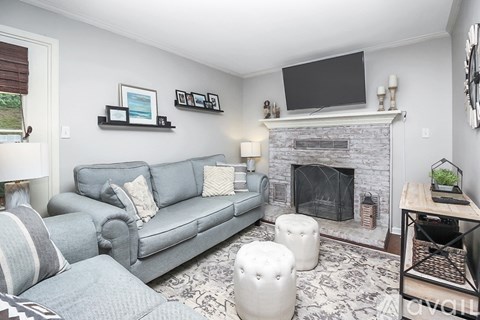 A living room with a grey couch, a fireplace, and a TV mounted above it.