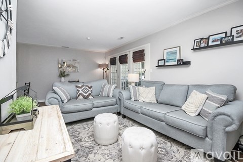 A living room with a grey couch, a wooden table, and a rug.