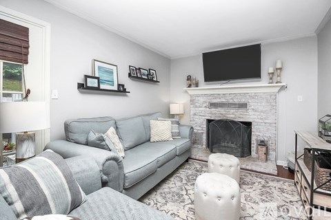 A living room with a grey couch and a fireplace.